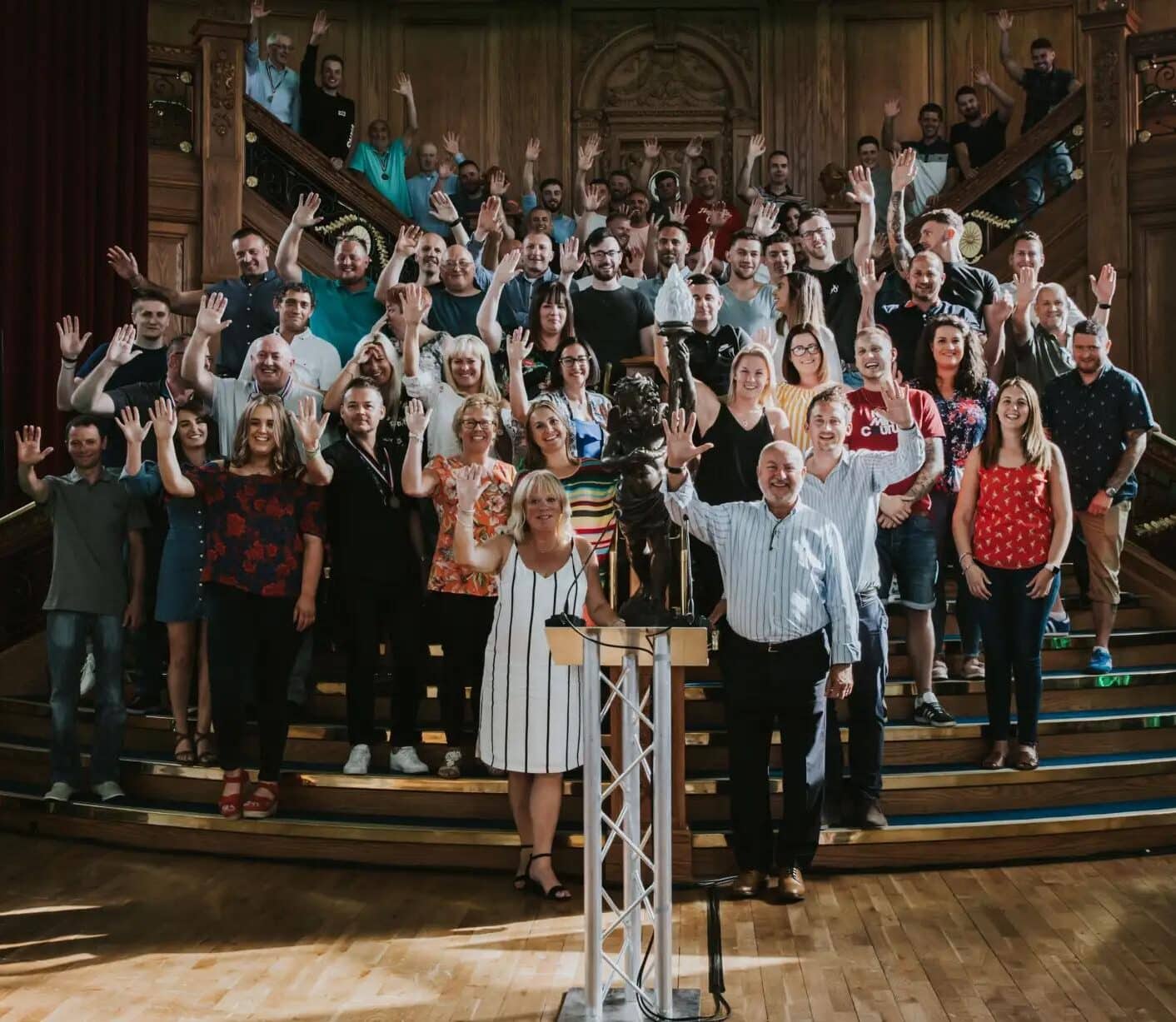 Employees of Smiley Monroe standing together on a staircase, smiling and waving at the camera